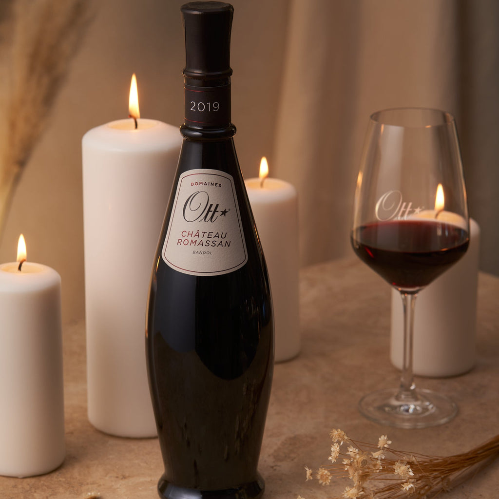 Bottle of Domaines Ott Chateau Romassan Bandol Rouge red wine with a glass and candles on a table