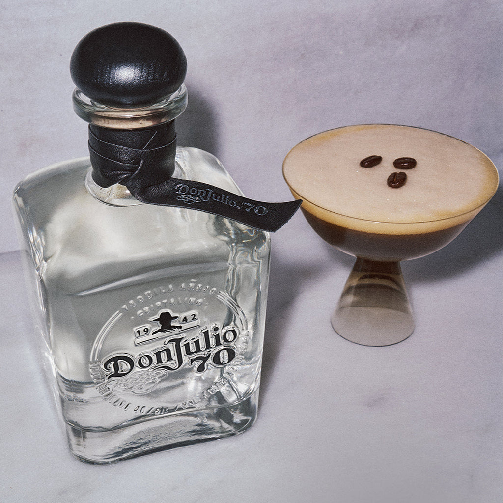 Don Julio 70 Cristalino tequila bottle with a espresso martini cocktail glass on a light gray background