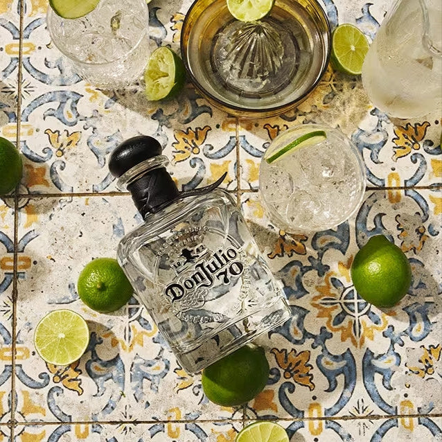Load image into Gallery viewer, Don Julio 70 tequila bottle with lime wedges on a patterned tile surface