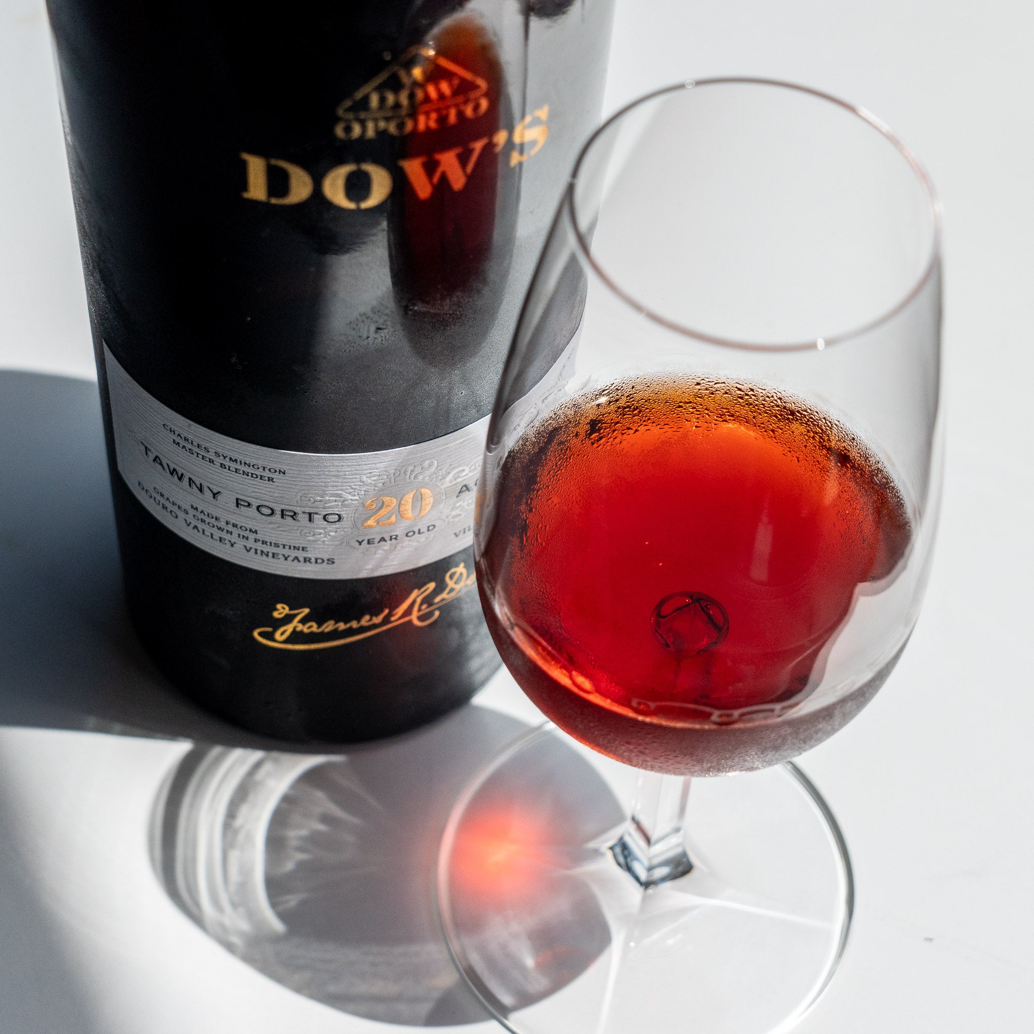 Load image into Gallery viewer, Bottle and glass of Dow's Tawny Porto wine on a reflective surface