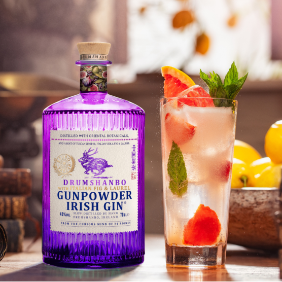 Load image into Gallery viewer, Drumshanbo Gunpowder Irish Fig &amp; Laurel Gin bottle with a cocktail garnished with fruit and mint leaves.
