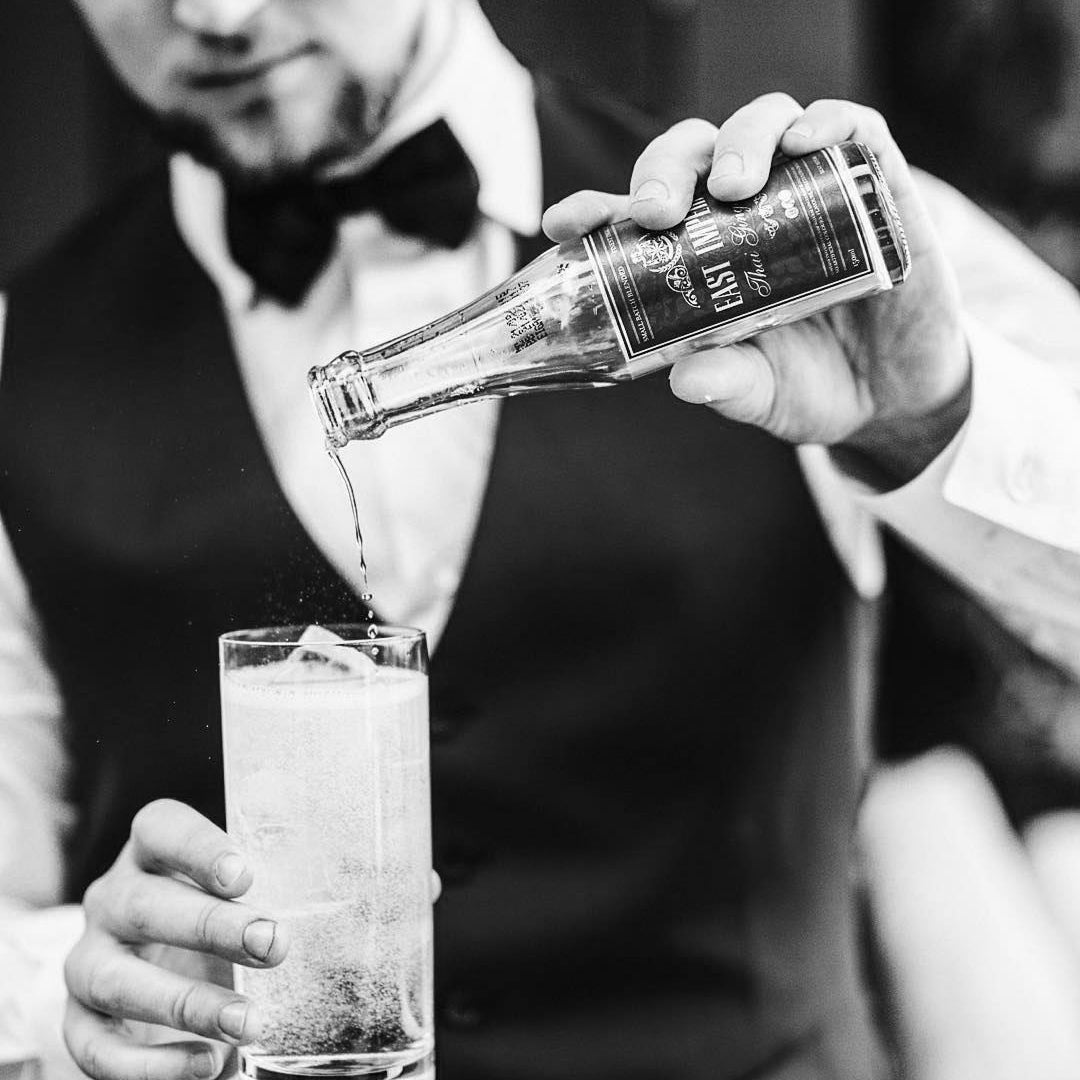 Load image into Gallery viewer, Barman pouring East Imperial Soda Water from a bottle into a glass, with a focus on the action.