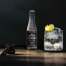Load image into Gallery viewer, Bottle of East Imperial Soda Water and a cocktail with ice and a lemon twist on a dark background