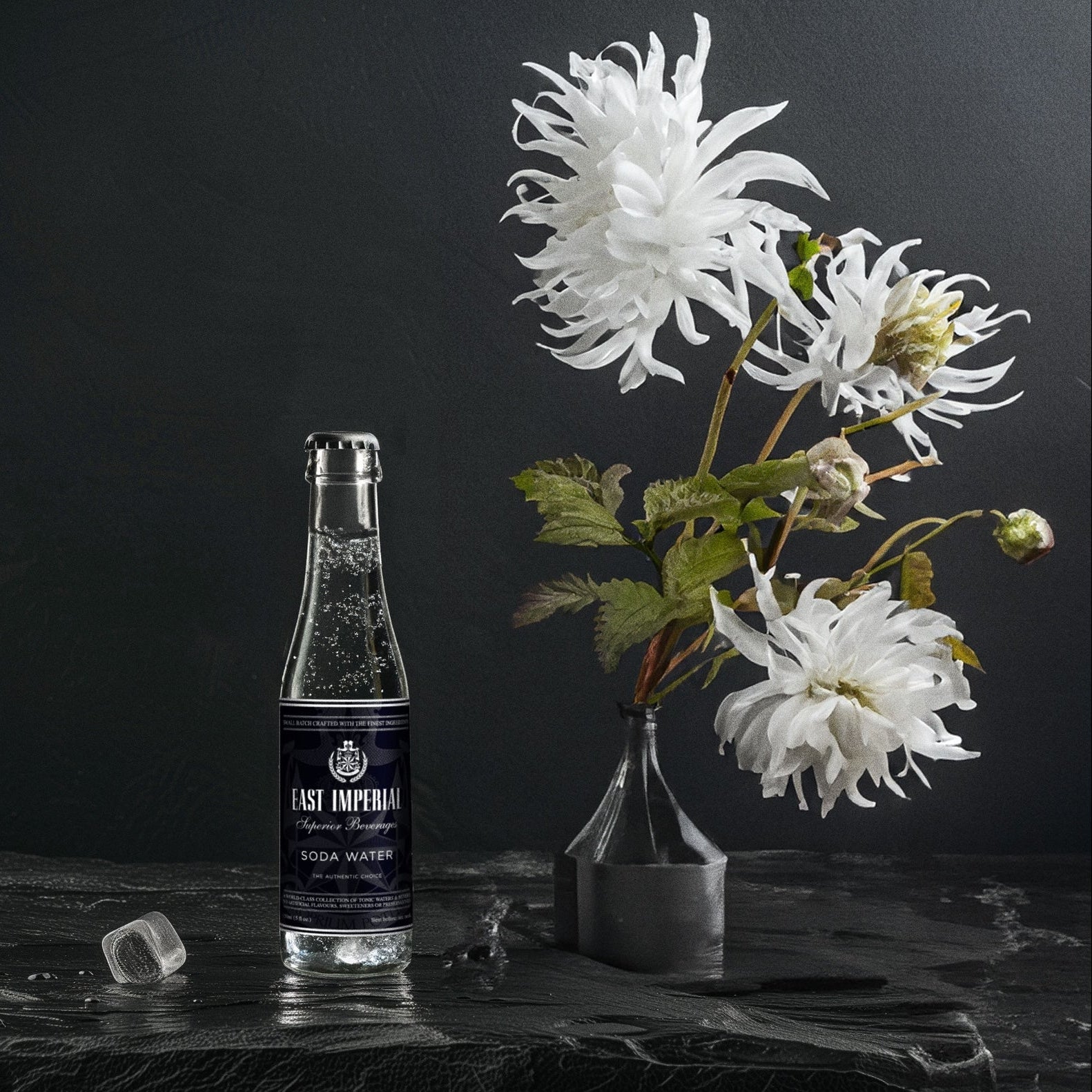 Load image into Gallery viewer, Bottle of East Imperial soda water with a vase of white flowers on a dark surface