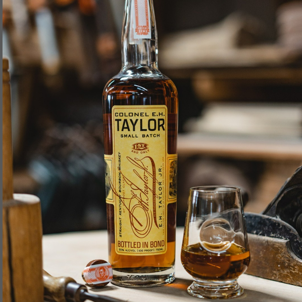 Load image into Gallery viewer, Bottle of Colonel E.N. Taylor whiskey with a glass on a bar counter.