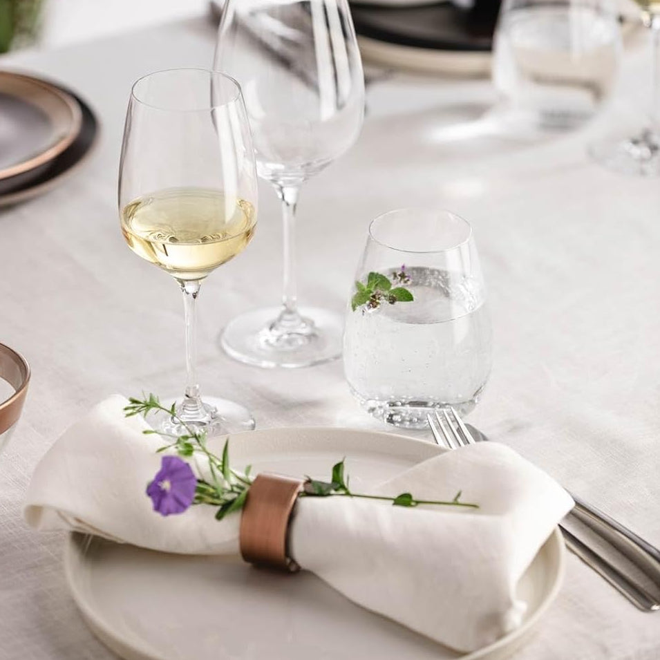 Load image into Gallery viewer, Dining table setting with wine glasses, plates, and a napkin with floral design.