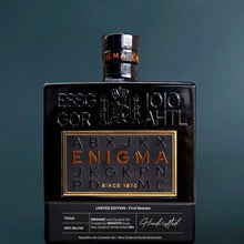 Load image into Gallery viewer, Black bottle of Enigma gin with gold text on a dark background