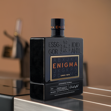 Load image into Gallery viewer, Black bottle of Enigma gin on a reflective surface with a blurred background