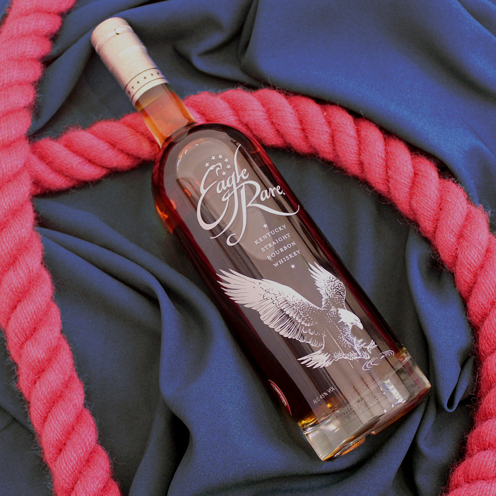 Load image into Gallery viewer, Whiskey bottle with intricate label on dark fabric background