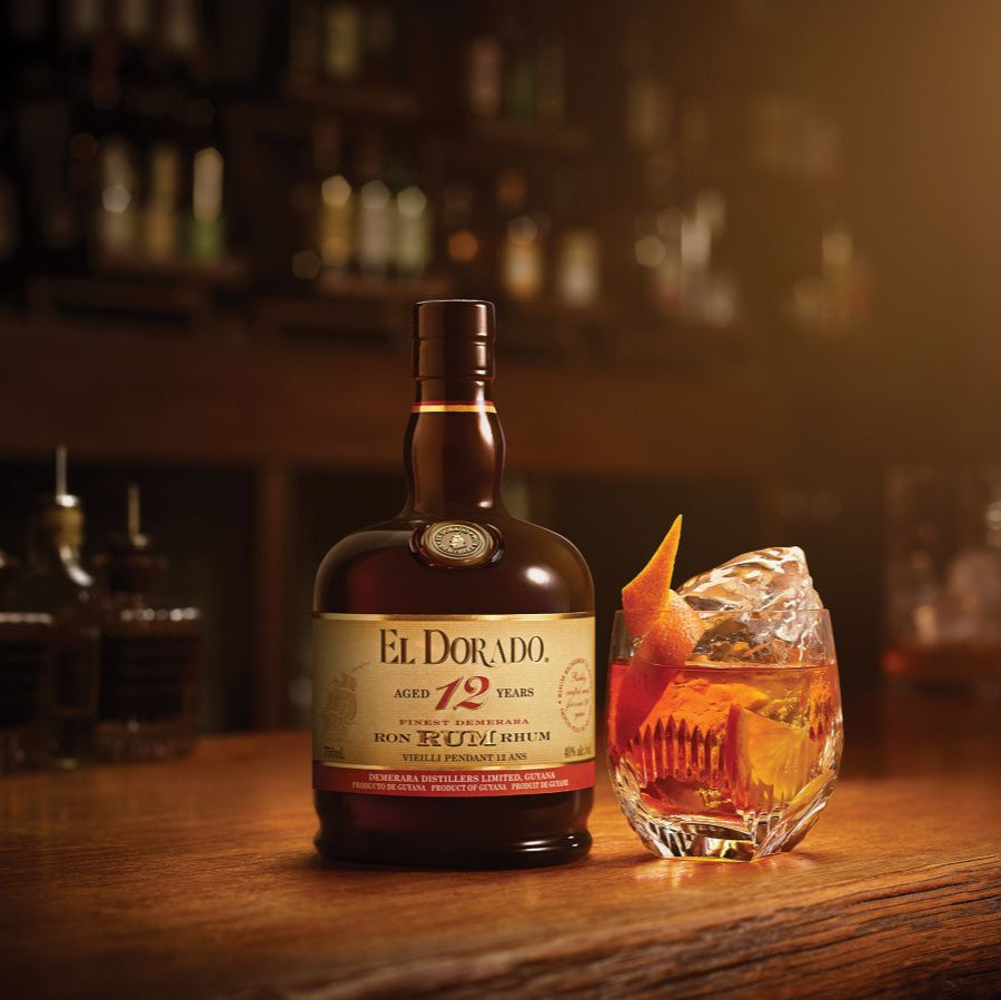 Load image into Gallery viewer, El Dorado 12-year-old rum bottle with a cocktail on a bar