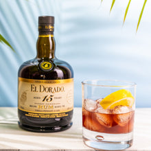 Load image into Gallery viewer, El Dorado 15-year-old rum bottle with a glass of cocktail on a light surface.