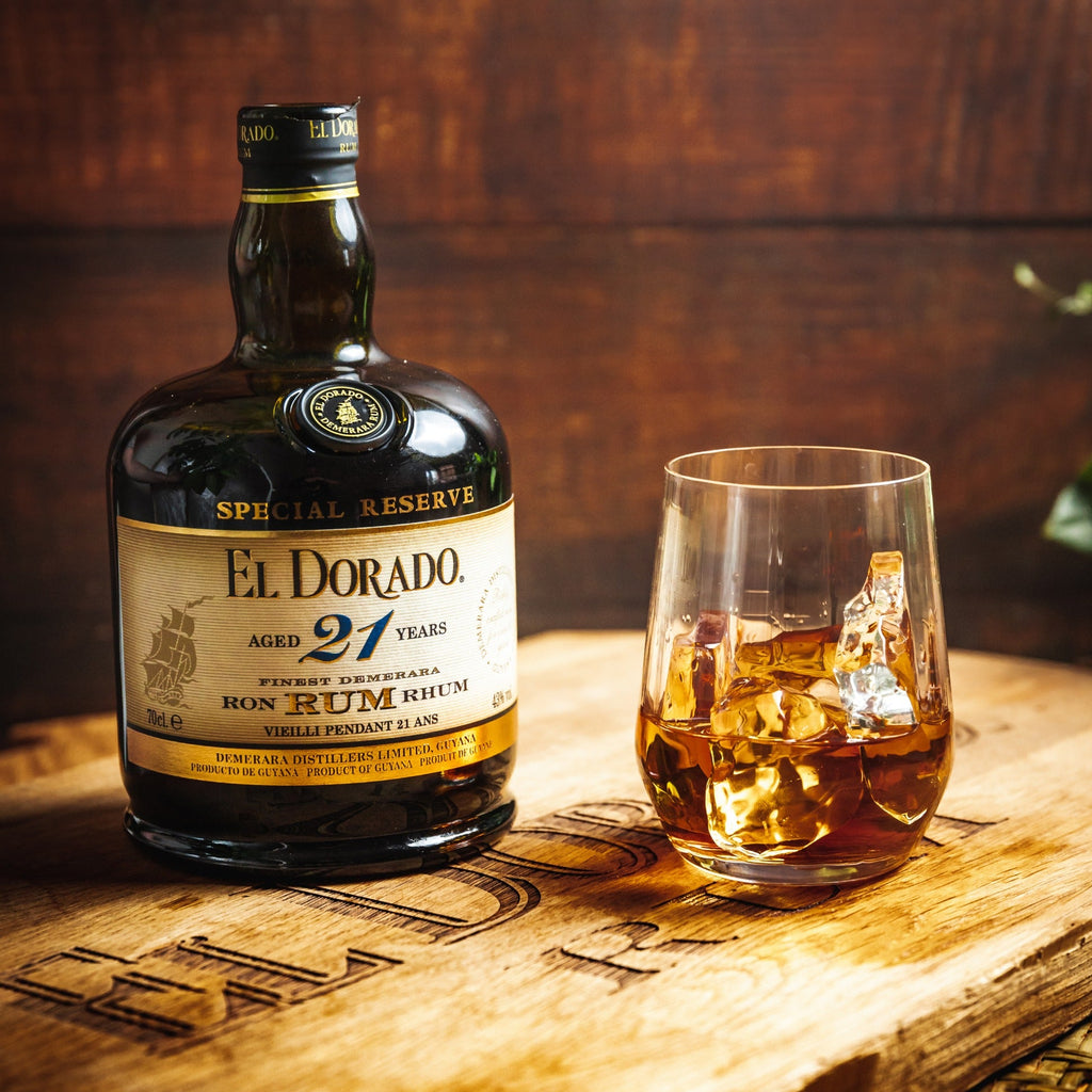 El Dorado Special Reserve 21-year-old rum bottle with a glass of rum on a wooden surface.