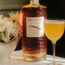 Load image into Gallery viewer, Bottle of Eminente-Reserva-7-Year-Old-Rum with a cocktail and flowers on a table