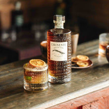 Load image into Gallery viewer, Bottle of Eminente-Reserva-7-Year-Old-Rum on a wooden bar with a glass of whiskey and an orange slice.