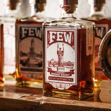 Load image into Gallery viewer, Bottle of Few Straight Bourbon Whiskey on a wooden surface with other bottles in the background.