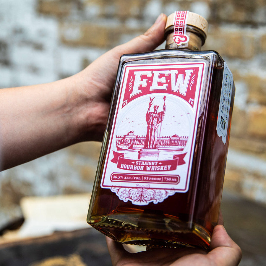 Load image into Gallery viewer, Bottle of Few Straight Bourbon Whiskey held by a hand with a blurred background
