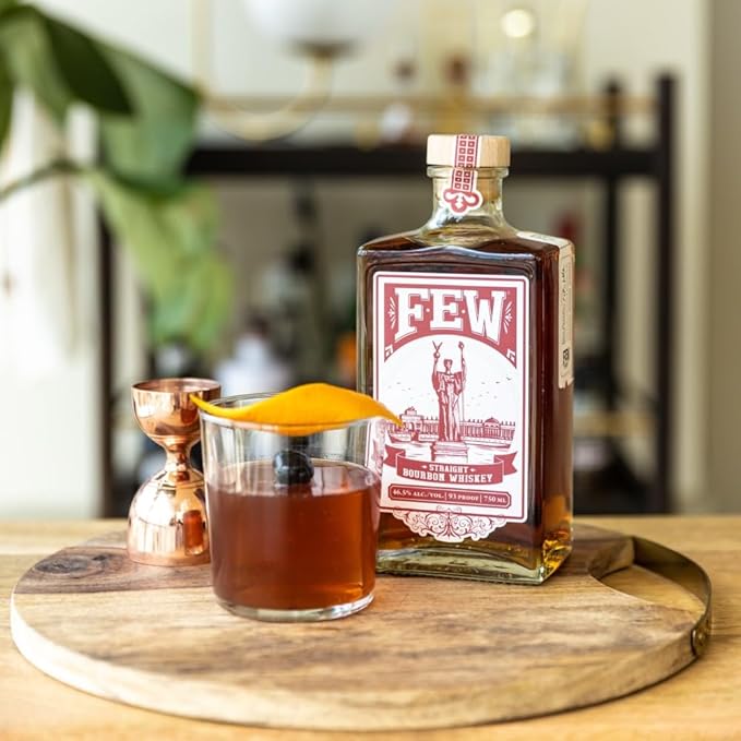 Load image into Gallery viewer, Bottle of FEW whiskey with a glass of whiskey on a wooden tray.
