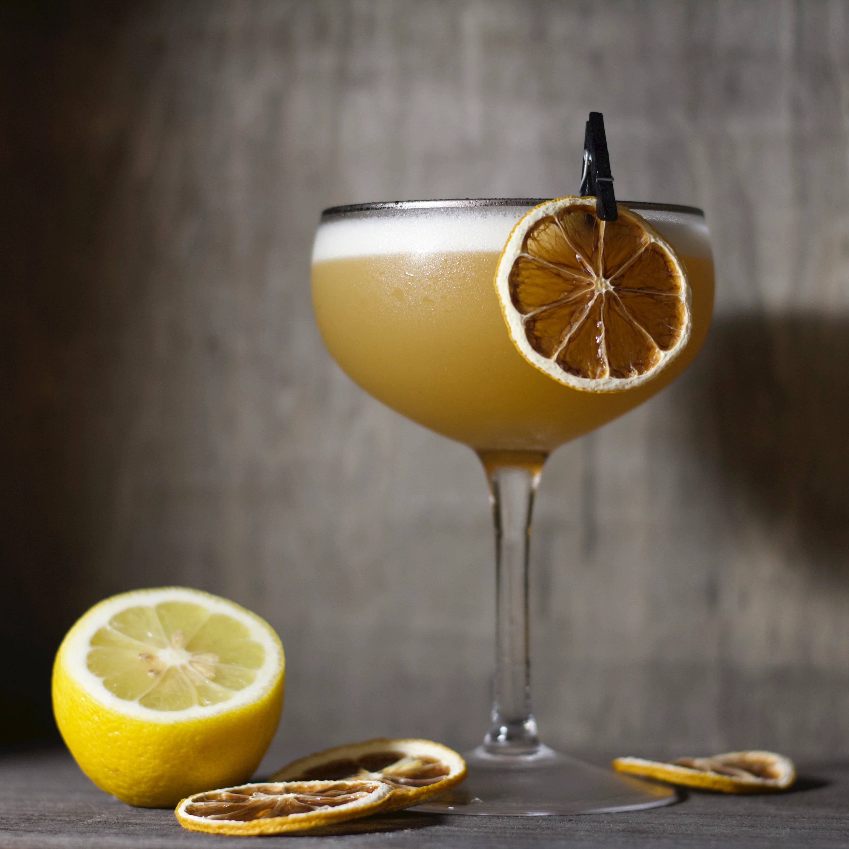 Load image into Gallery viewer, Cocktail in a glass with lemon garnish on a wooden surface