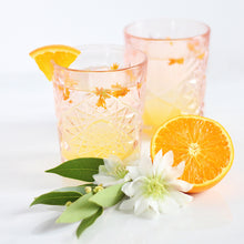 Load image into Gallery viewer, Two pink glasses with floral patterns, orange slices, and white flowers on a light background