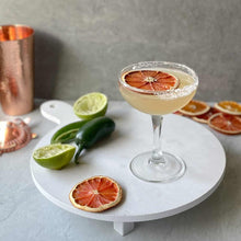 Load image into Gallery viewer, Cocktail with orange garnishes on a marble tray with a grey background
