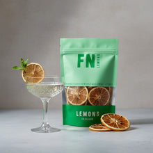 Load image into Gallery viewer, FN Lemons dried lemons with a glass of lemon-sliced cocktail on a neutral background