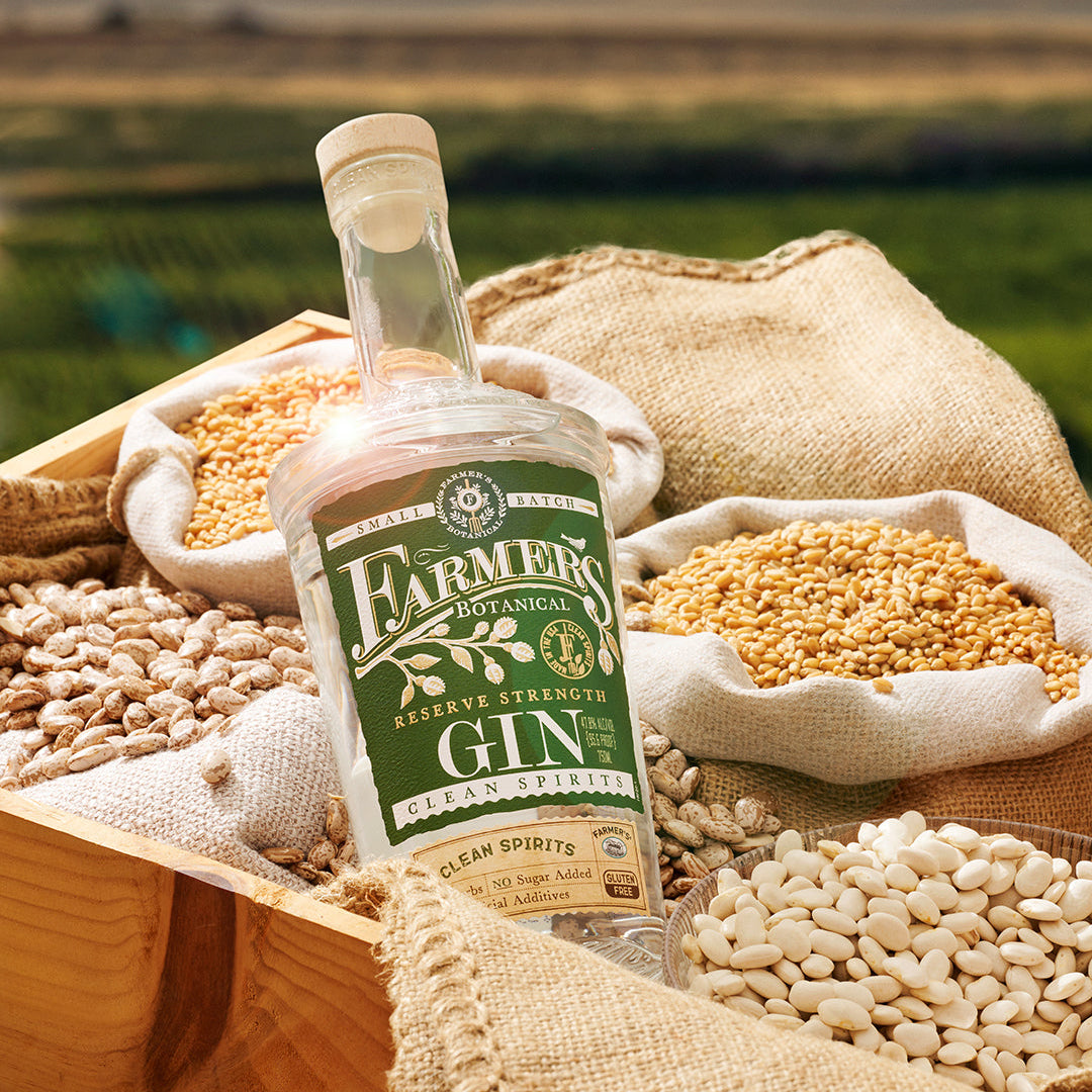 Load image into Gallery viewer, Bottle of Farmers Botanical Gin surrounded by grains and seeds in a rustic setting