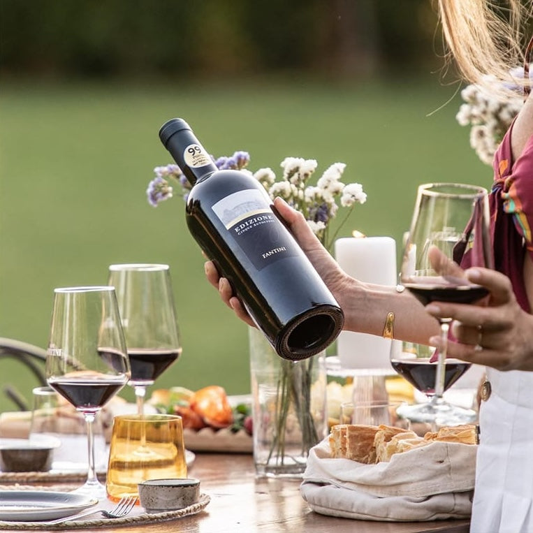 Load image into Gallery viewer, A woman holding a bottle of Farnese Fantini Edizione Cinque Autoctoni red wine in her hand