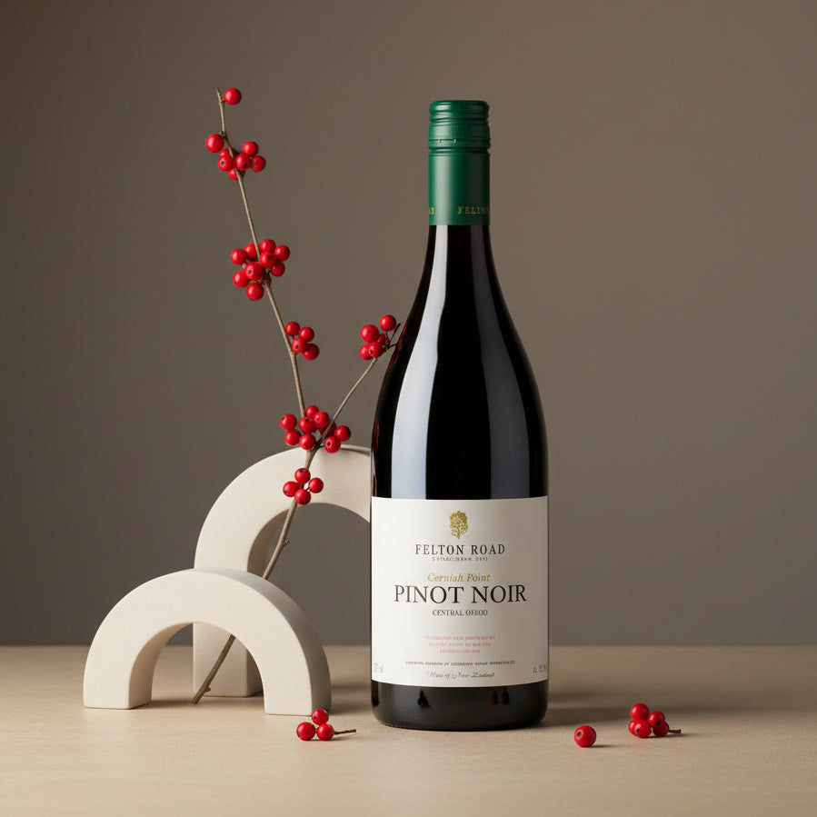Load image into Gallery viewer, A bottle of Felton Road Cornish Point Pinot Noir red wine stands on a light wood surface against a warm taupe background, styled with a white geometric arch and red berry branches.
