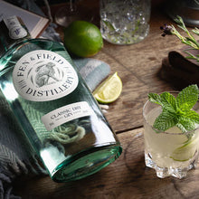 Load image into Gallery viewer, Bottle of Fen &amp; Field Distillery Classic Dry Gin on a wooden surface with a cocktail garnished with lime and mint.