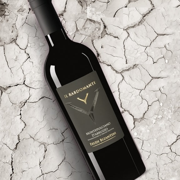 Load image into Gallery viewer, A bottle of the Feudi Bizantini Il Rabdomante Montepulciano on a dried mud bed