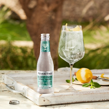 Load image into Gallery viewer, Fever-Tree elderflower tonic water bottle with a glass of lemonade on a wooden tray outdoors.