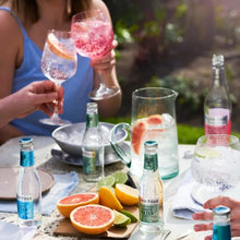 Load image into Gallery viewer, People enjoying a refreshing tonics drink outdoors with bottles and glasses on a table.