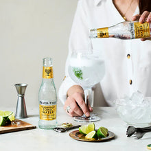 Load image into Gallery viewer, Person preparing a cocktail with Fever-Tree Indian tonic water on a white countertop.