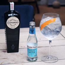 Load image into Gallery viewer, Bottle of Scapegrace gin, bottle of Fever-Tree Mediterranean tonic water, and a glass of gin and tonic on a wooden table.