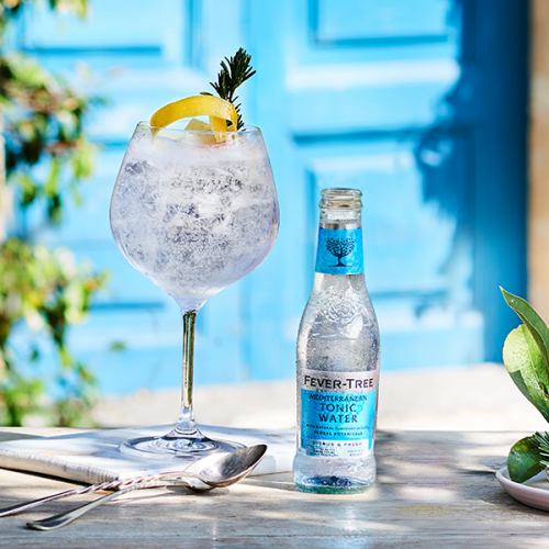 Load image into Gallery viewer, Fever-Tree tonic water bottle with a glass of tonic water on a table outdoors.