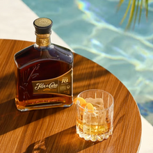 Load image into Gallery viewer, Bottle of Flor de Cana 18 year old Rum  and a glass with a pool in the background
