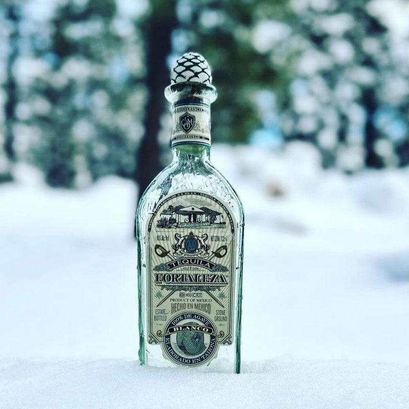Fortaleza Blanco Tequila bottle with snow on a blurred snowy background