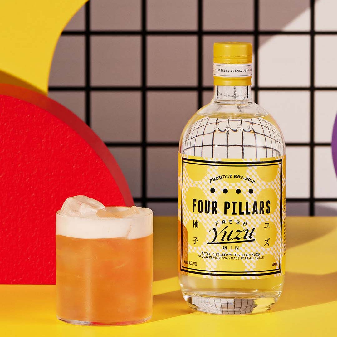 Load image into Gallery viewer, Bottle of Four Pillars Fresh Yuzu Gin with a cocktail on a colorful background