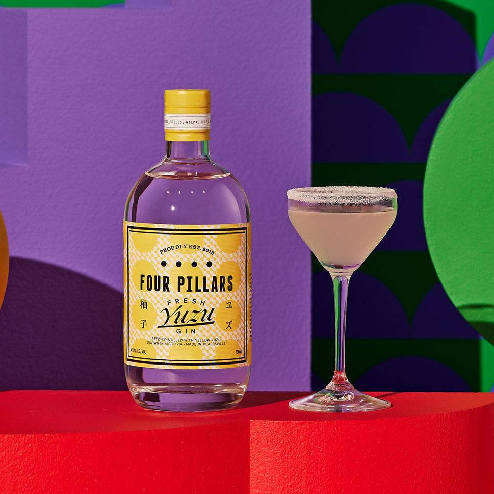Load image into Gallery viewer, Four Pillars Yuzu Gin bottle with a cocktail on a colorful geometric background