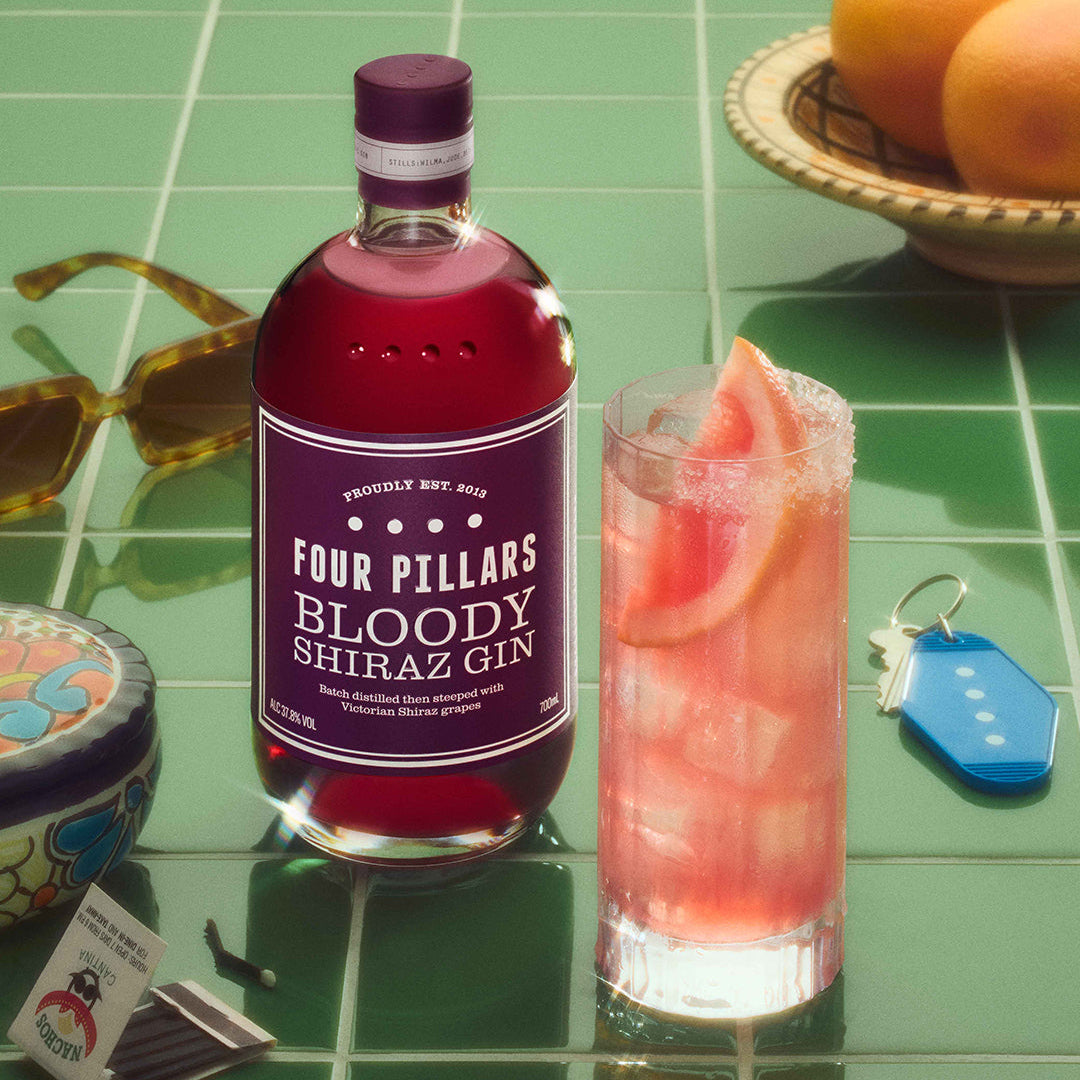 Load image into Gallery viewer, Four Pillars Bloody Shiraz Gin bottle with a cocktail on a green tiled surface.