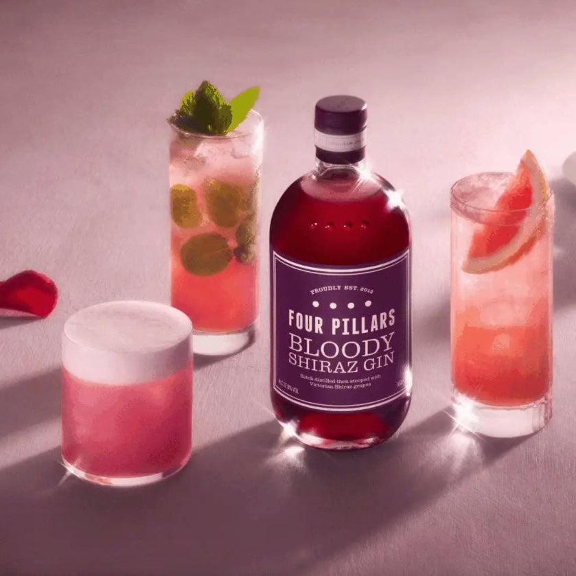 Load image into Gallery viewer, Bottle of Fox Pillars Bloody Chinatown cocktail with two glasses filled with the drink on a dark surface.