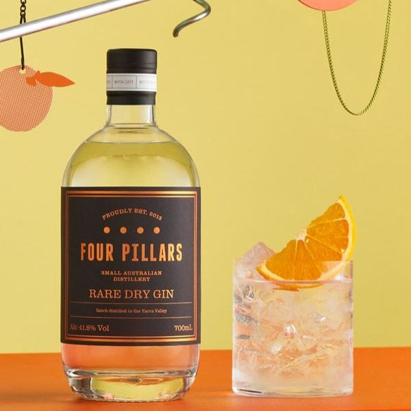 Load image into Gallery viewer, Four Pillars Rare Dry Gin bottle with a cocktail garnished with an orange slice on a colorful background