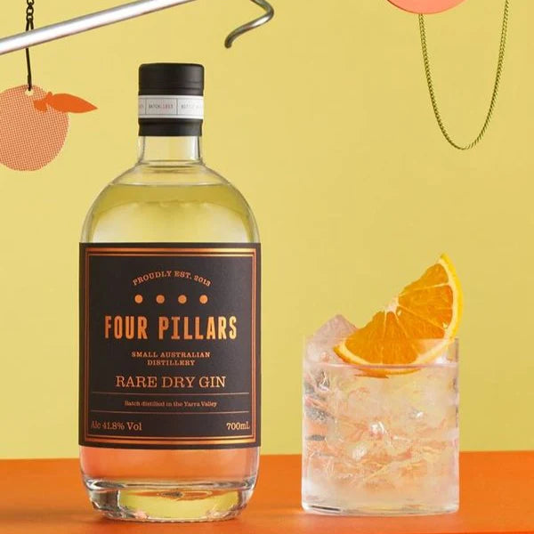 Load image into Gallery viewer, A bottle an a full glass of gin in a glass with ice and a orange wedge in it with a yellow background