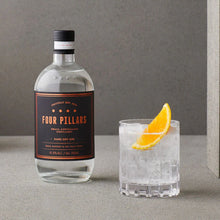 Load image into Gallery viewer, Four Pillars gin bottle with a cocktail garnished with an orange slice on a gray surface.