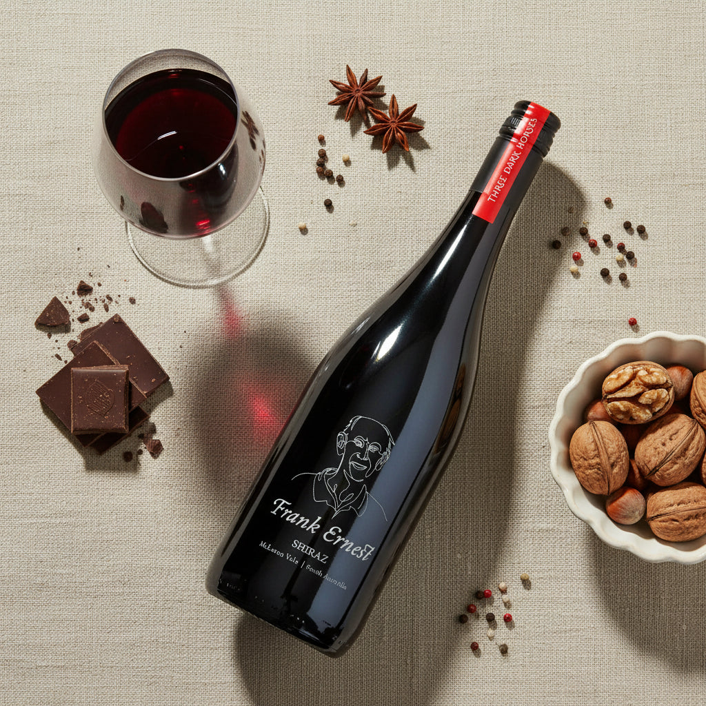 Load image into Gallery viewer, Bottle of Frank Ernest Shiraz red wine with a glass of red wine, chocolates, and nuts on a textured surface.