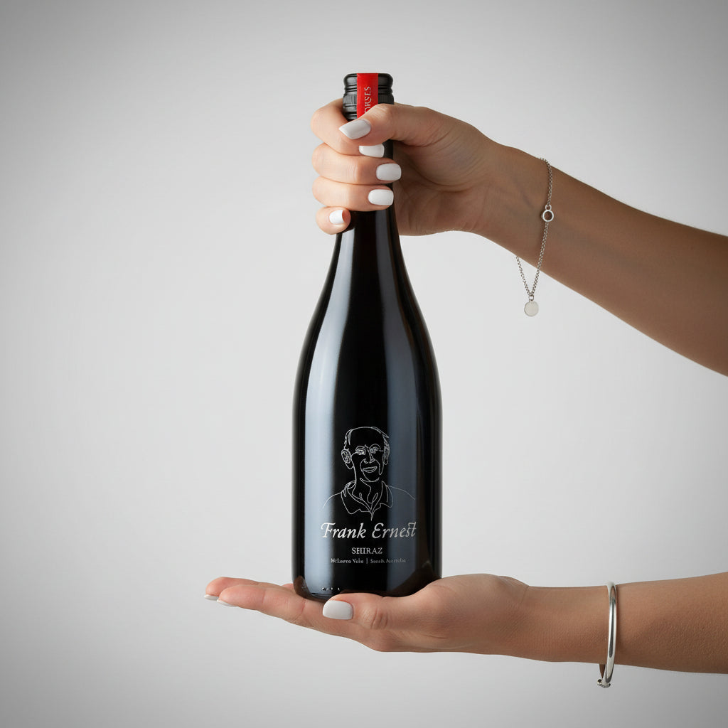 Load image into Gallery viewer, Hand holding a bottle of Frank Ernest Shiraz red wine against a plain background