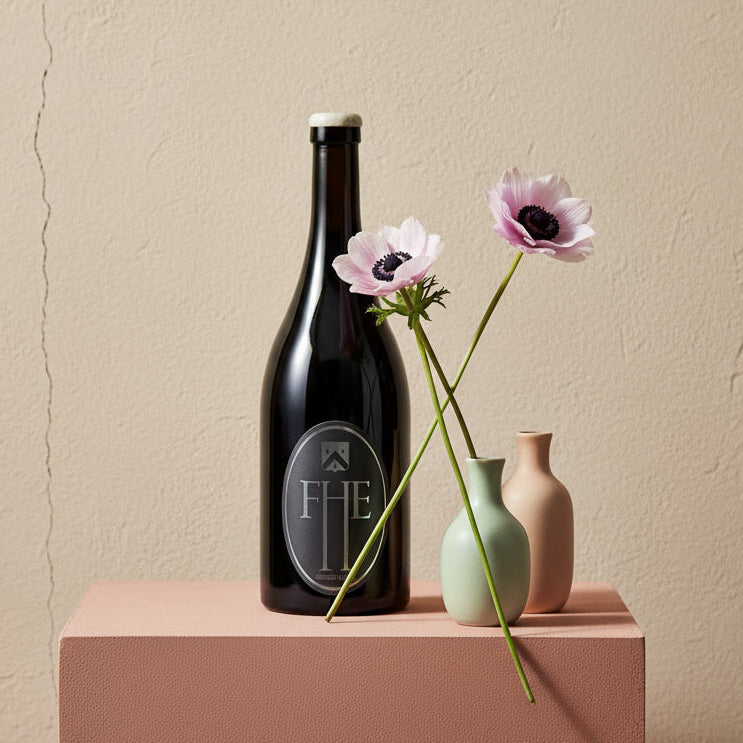 A bottle of Frenchmans Hill Expatrius Syrah on a pink platform against a beige wall
