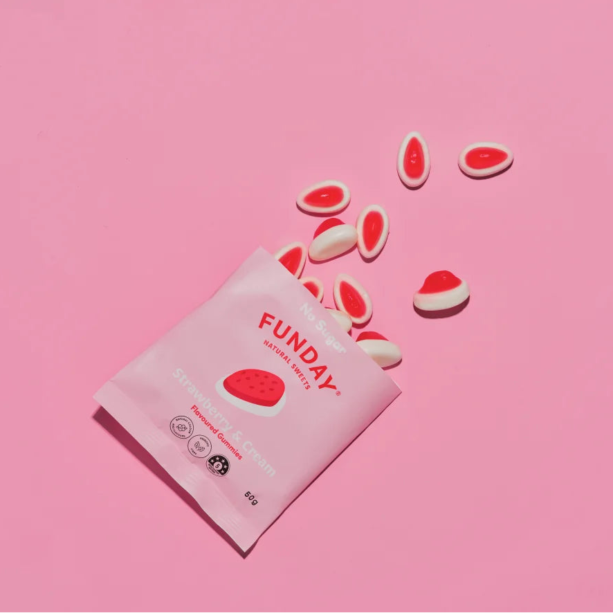 Load image into Gallery viewer, A 50g pouch of Funday Strawberry &amp; Cream Gummies with several gummies scattered on a solid pink background.