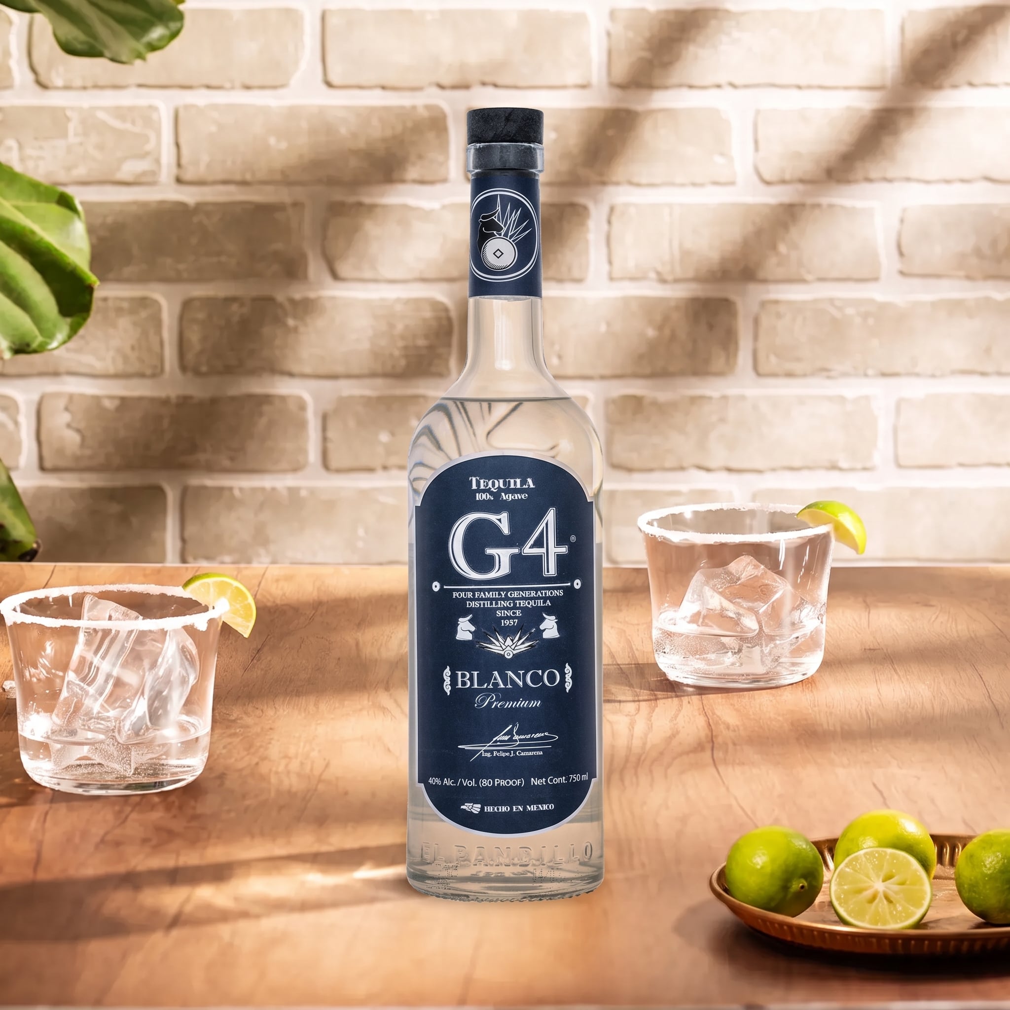 Load image into Gallery viewer, A bottle of G4 Tequila Blanco stands on a wooden table in a bar-like setting, with two clear rocks glasses, lime wedges, and a small tray of limes against a light brick wall background.