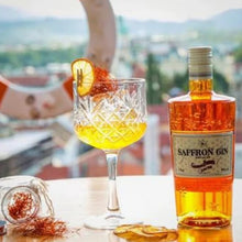 Load image into Gallery viewer, A bottle of gin and a glass of gin and tonic on a table with a blurry background